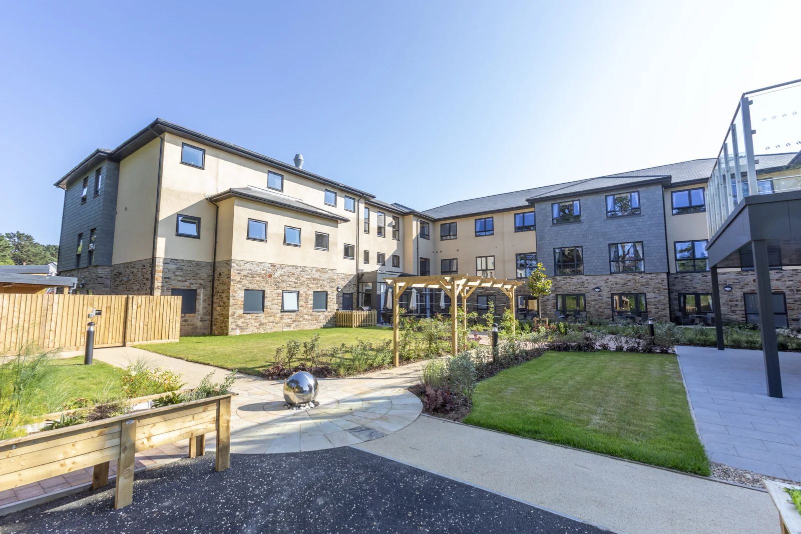 Bayards Court care home seen across its courtyard garden, with balconies and the three-storey elevation behind