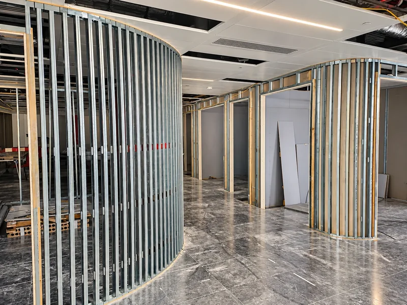 Curved metal stud partitions with timber door linings on a tiled office floor