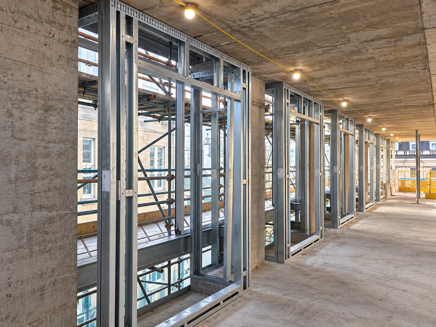 Steel framing system infill walls between concrete slabs with window openings formed