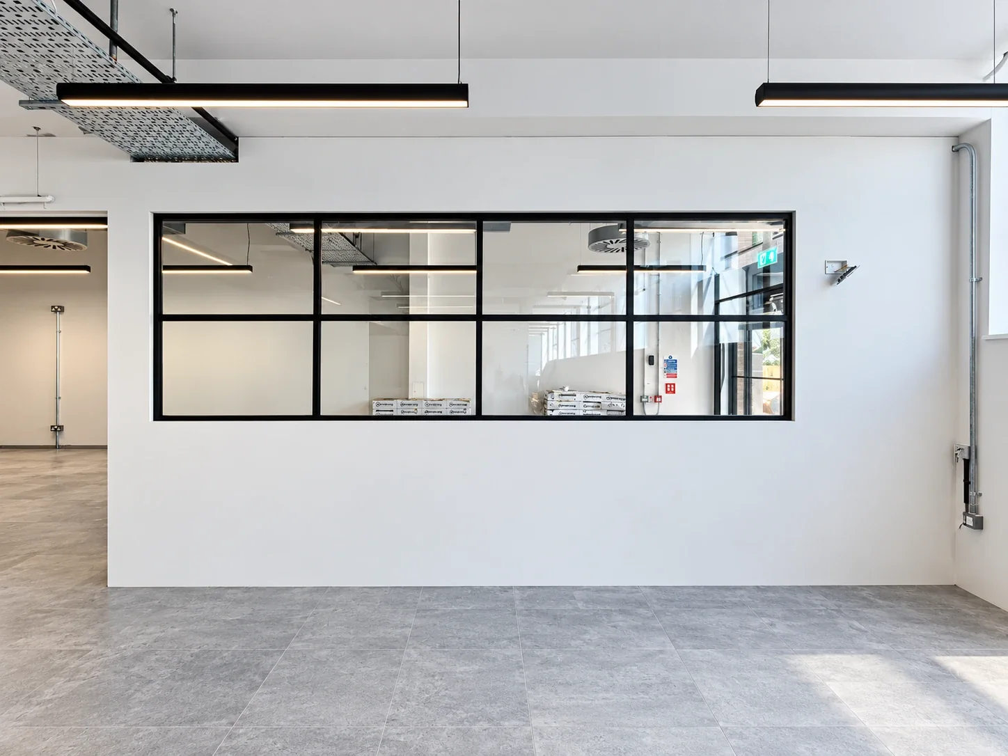 Black-framed internal glazed screen set into a white plastered partition