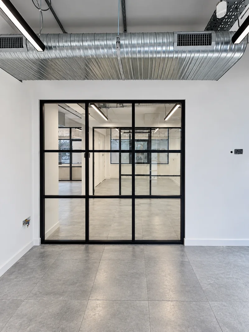 Full-height black-framed glazed screen dividing an office floor